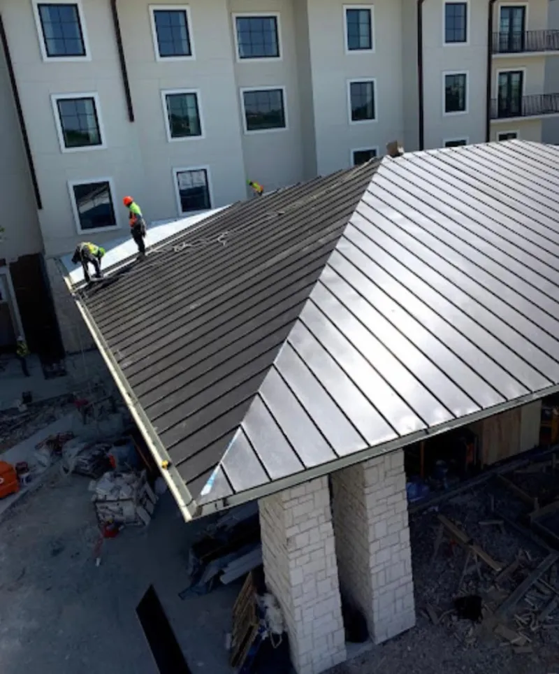 Crew installing standing seam metal roof panels on a commercial project in Sandpoint